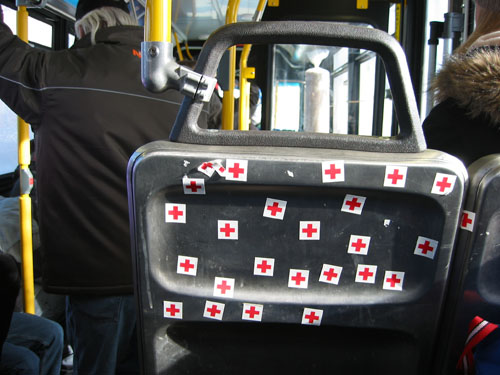 Red Cross stickers on the back of a bus seat.