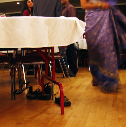 Some shoes under a table at the WATSA semi-formal.  AJ and Maya can be seen talking in the background.