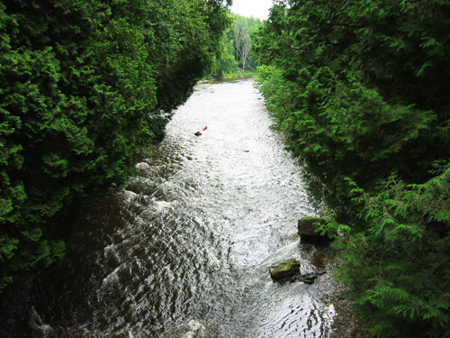 Two people inner tubing in the Grand River at the Elora camp grounds.